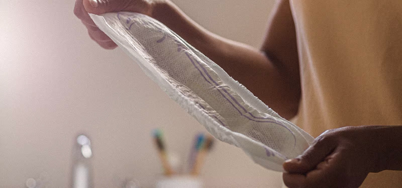 Una mujer poniéndose una compresa TENA Una mujer poniéndose una compresa TENA